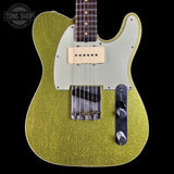 A close-up of a gold glitter electric guitar body with a cream pickguard, dual humbucker pickups, and chrome hardware, shown against a black background with a Tone Shop watermark in the top left.