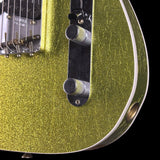 Close-up of a glittery metallic yellow-green electric guitar body with chrome control knobs, bridge, and pickups against a black background.