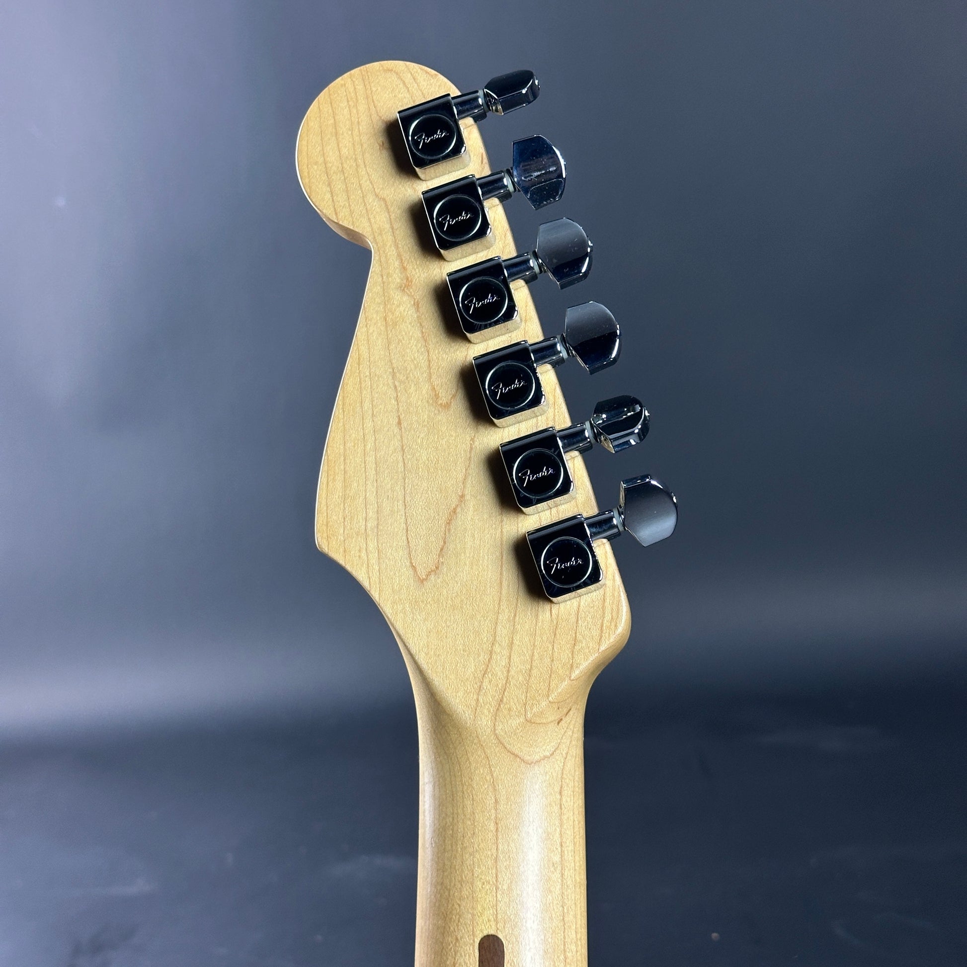 Guitar headstock with tuning pegs on a dark gray background