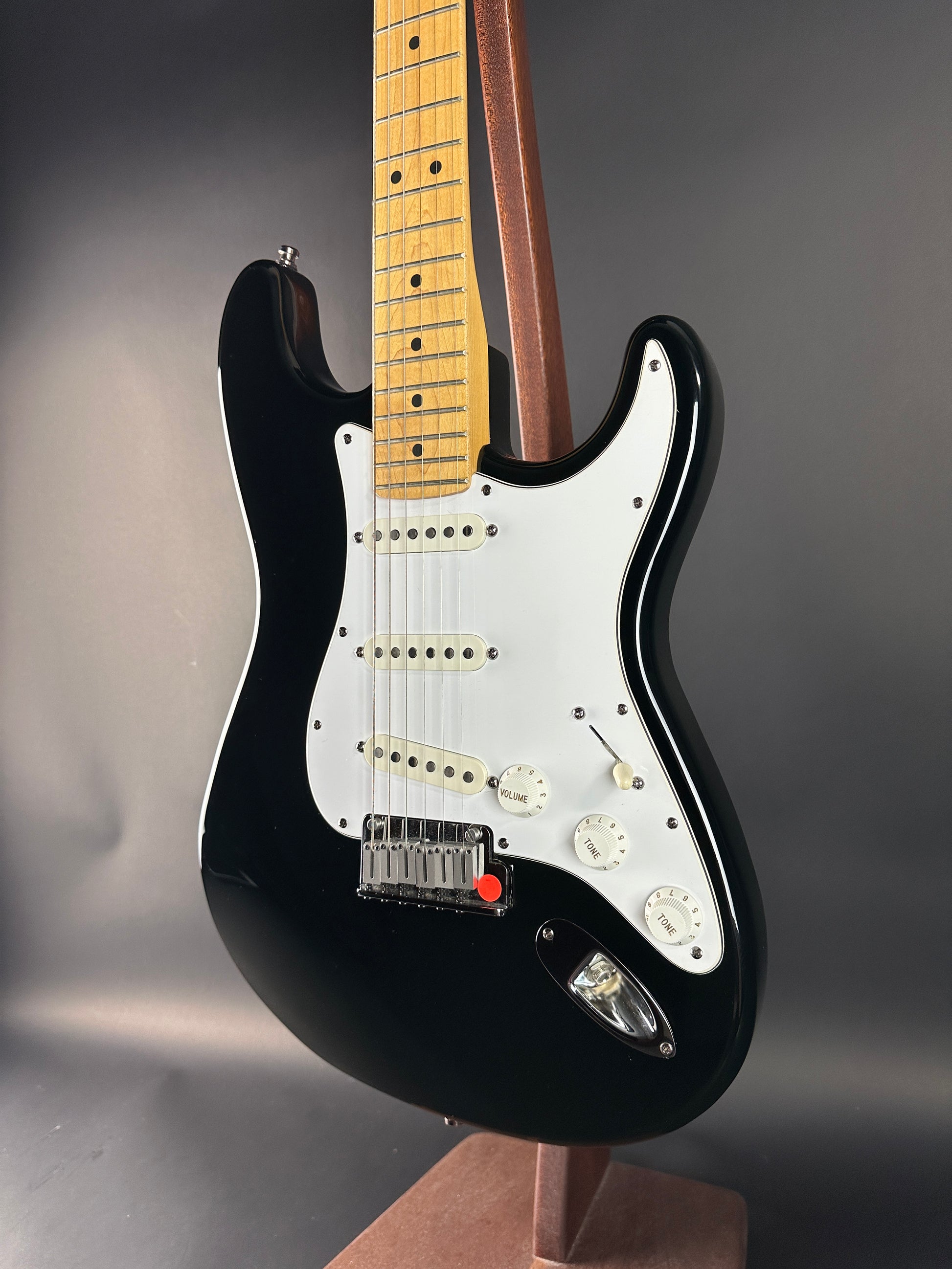 Black electric guitar with a white pickguard on a dark background