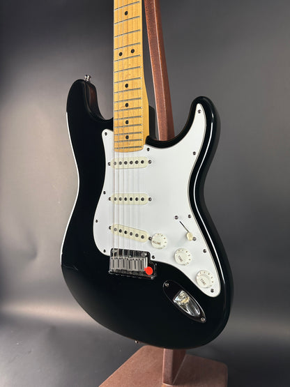 Black electric guitar with a white pickguard on a dark background