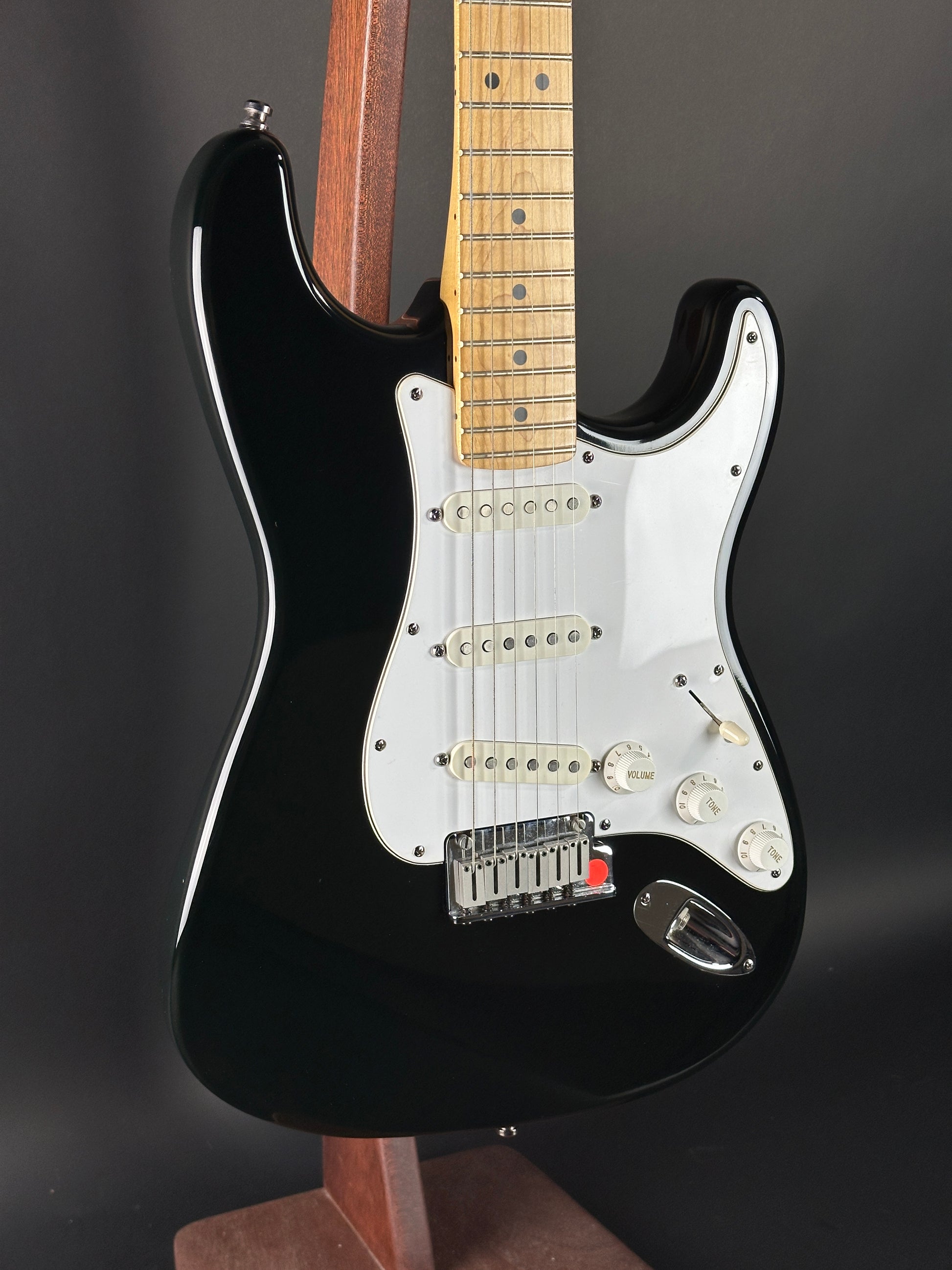 Black electric guitar with a white pickguard on a dark background