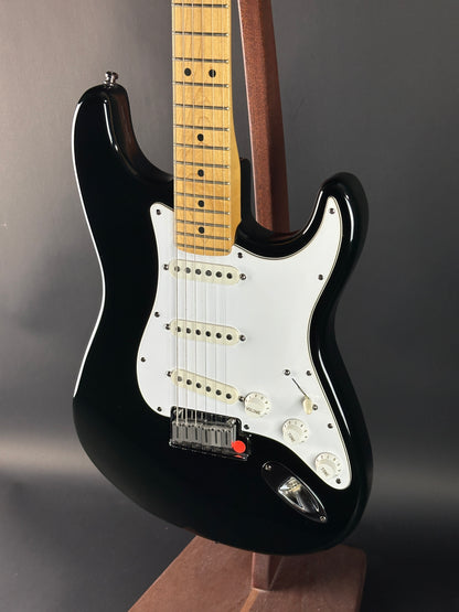 Black electric guitar with a white pickguard on a dark background