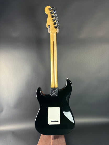 Black electric guitar with a wooden neck against a gray background