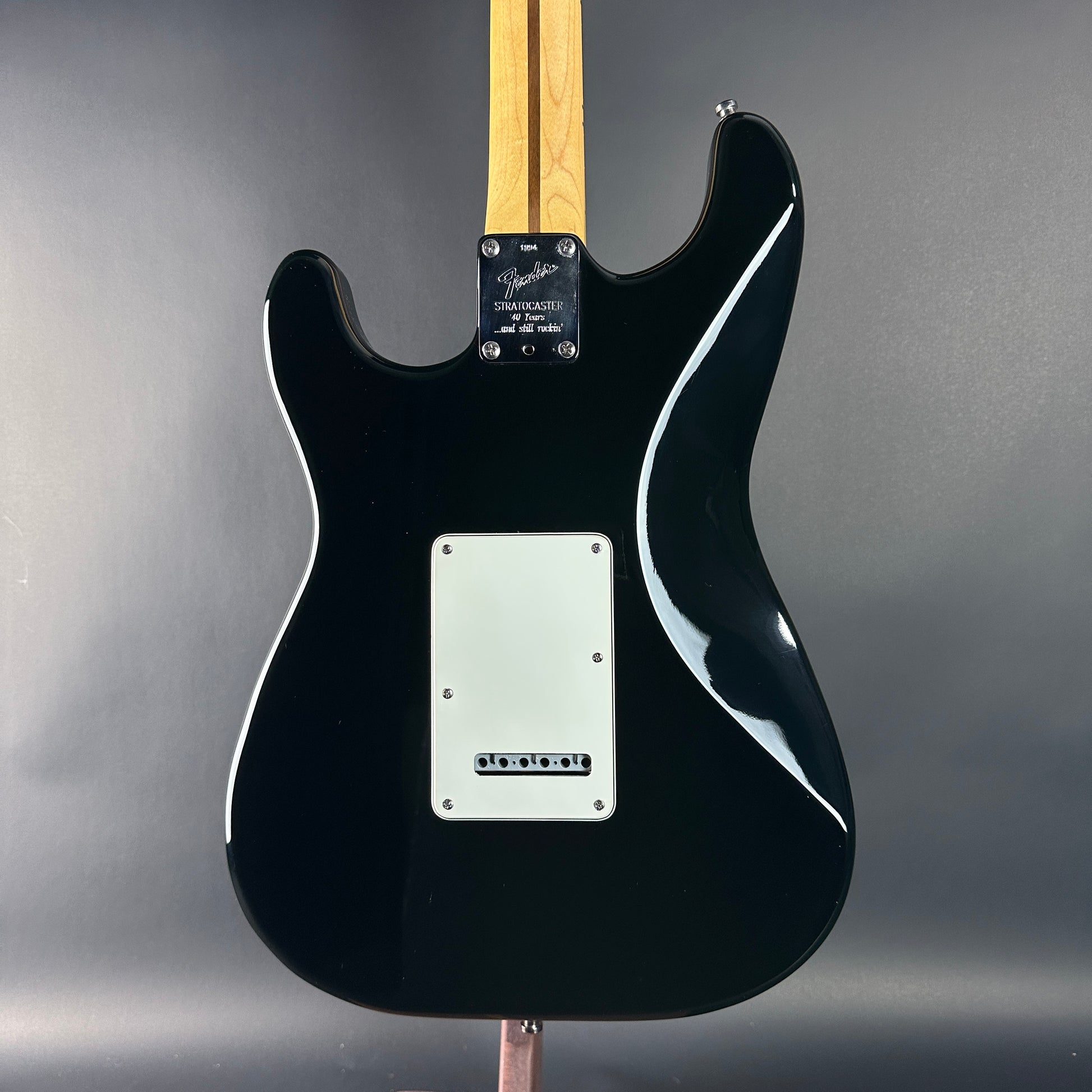 Black electric guitar with a Fender logo on a gray background