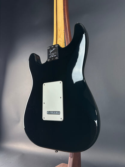 Black electric guitar body on a reflective surface with a gray background