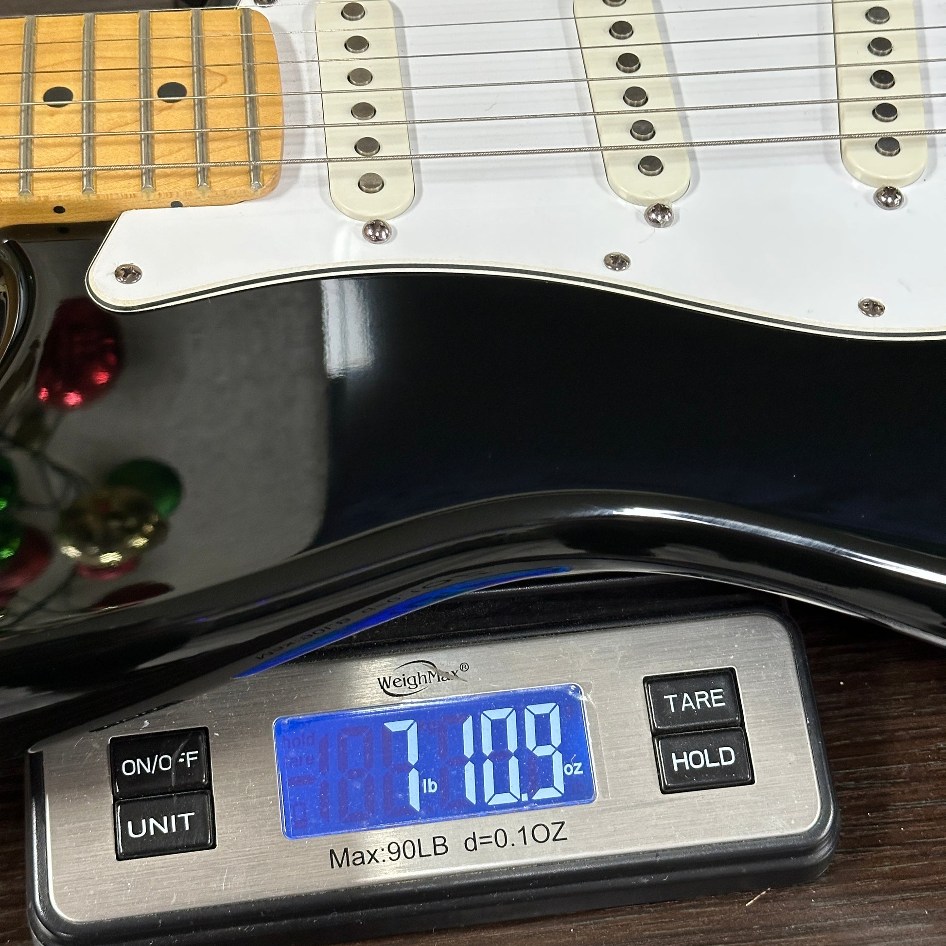 Digital scale displaying weight of a guitar on a wooden surface
