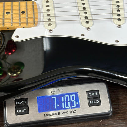 Digital scale displaying weight of a guitar on a wooden surface