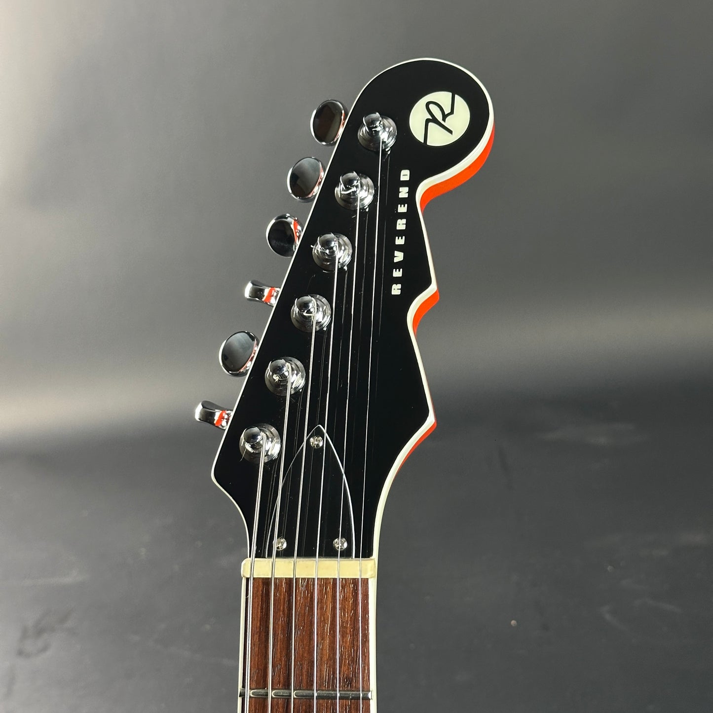 Guitar headstock with brand logo on a dark background