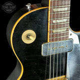Close-up of a guitar's neck and headstock with a black body.