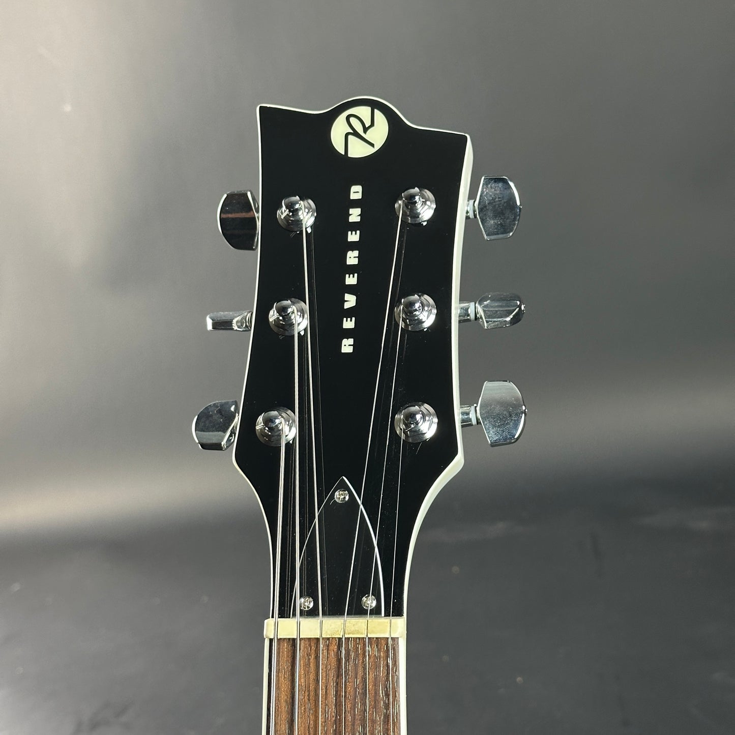 Guitar headstock with 'Reverend' branding on a dark background