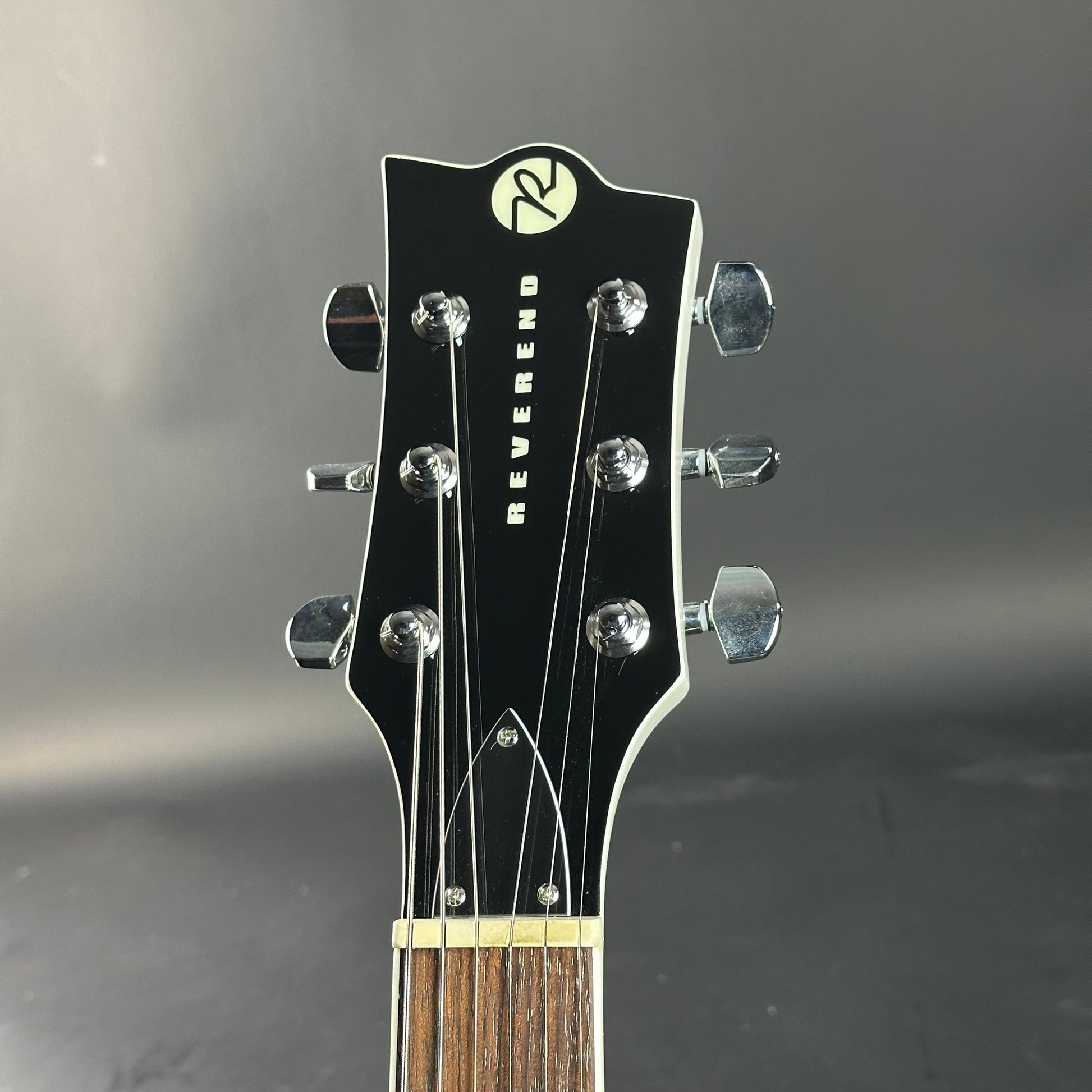 Guitar headstock with 'Reverend' branding on a dark background