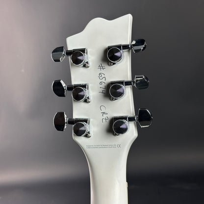 Close-up of a guitar headstock with tuning pegs on a gray background