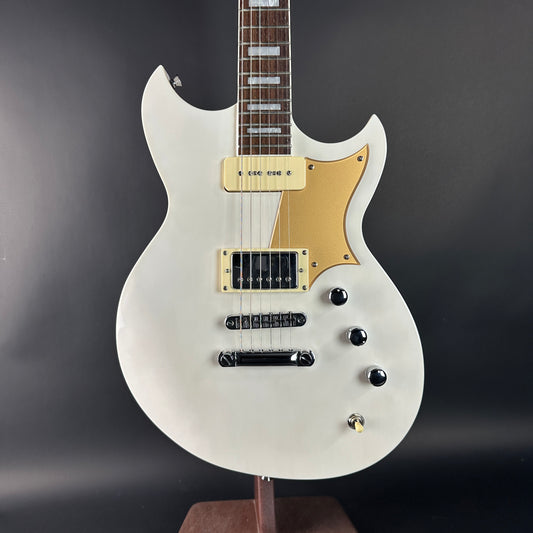 White electric guitar with gold accents on a dark gray background