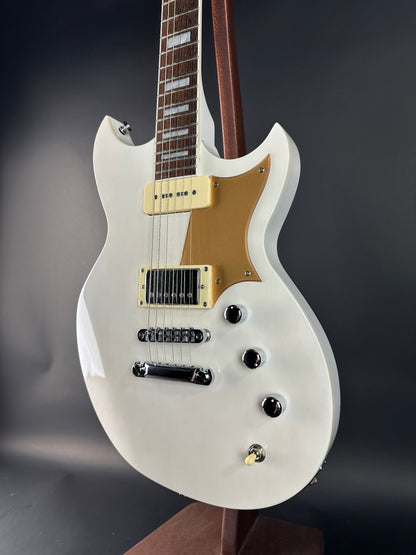 White electric guitar with a gold pickguard on a dark background