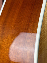 Close-up detail of a glossy brown wooden instrument body with a white edge strip and a warm wood top visible at the top.