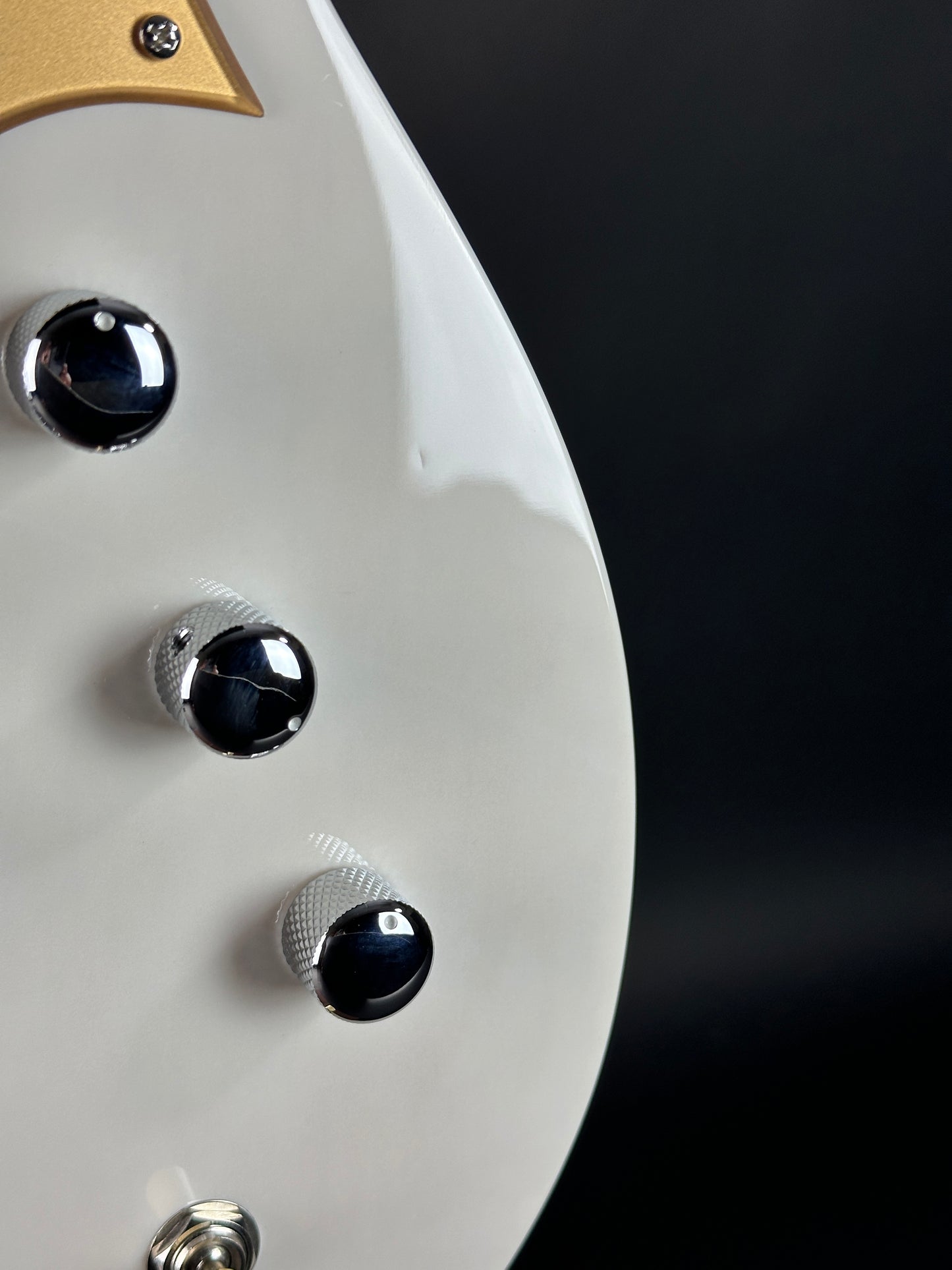 Close-up of a guitar headstock with control knobs against a dark background