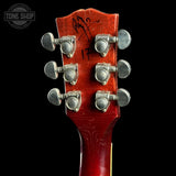 Close-up of a red guitar headstock with tuning pegs on a black background, featuring 'Tone Shop' logo.