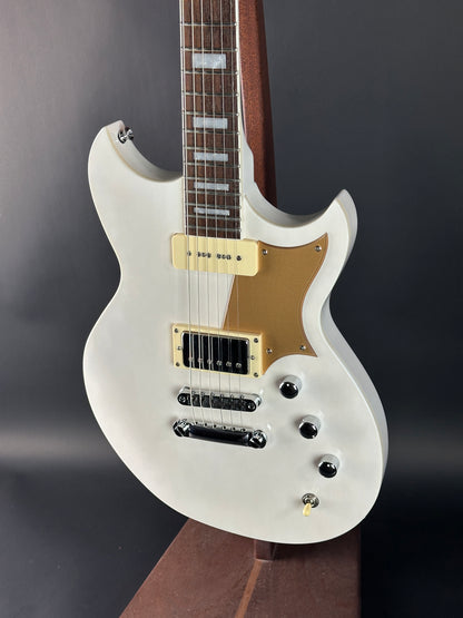 White electric guitar with gold hardware on a dark background