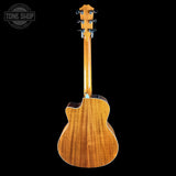The back of a wooden acoustic-electric guitar with a glossy natural wood finish, shown against a solid black background with a Tone Shop watermark in the top-left corner.