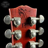 Close-up of a red guitar headstock with tuning pegs and 'Tone Shop' branding.