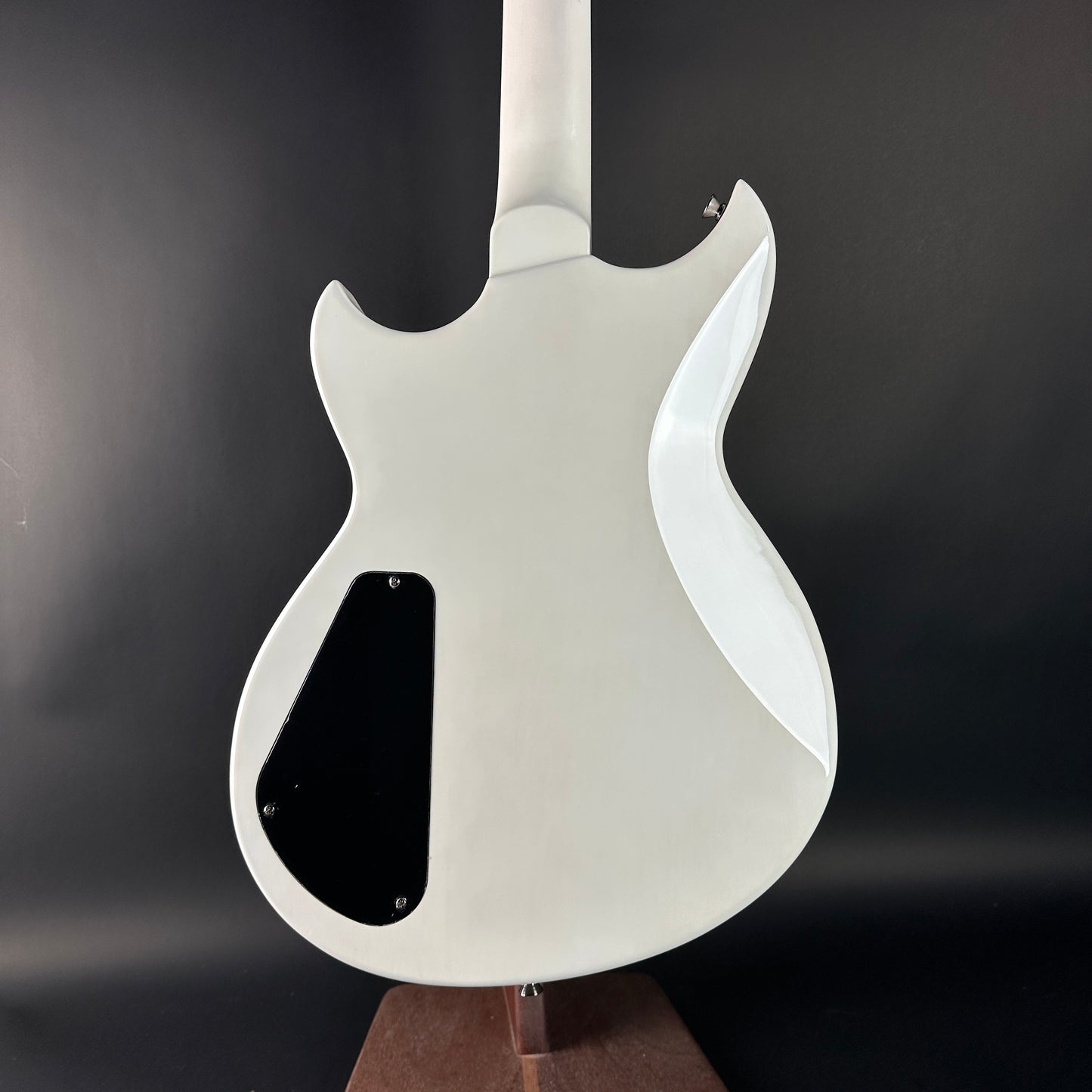 White electric guitar on a stand against a dark background
