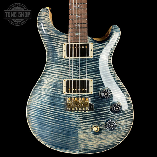 Blue electric guitar with a wavy pattern on a black background, featuring the Tone Shop logo.