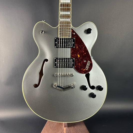 Silver electric guitar with a dark pickguard on a gray background