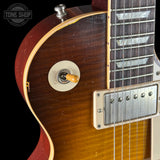Close-up of a guitar's neck and headstock with 'Tone Shop' branding.