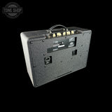 Guitar amplifier with control knobs on a black background, featuring 'Tone Shop' logo.