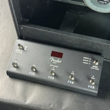 A Fender Effects Pedal unit in dark gray/black plastic with five footswitches and a small red display window, photographed close-up against a dark textured surface.