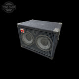 A vintage black speaker cabinet with two large front-facing speakers behind metal grilles, shown at an angle on a solid black background. A Tone Shop watermark is visible in the top-left corner.