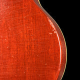 Close-up of a red guitar body with wood grain texture on a black background