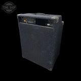 A black guitar amplifier cabinet with a textured front baffle, corner protectors, and a top carry handle, shown against a solid black background with a Tone Shop watermark in the top-left corner.