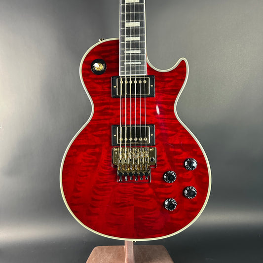 Red electric guitar on a stand with a gray background