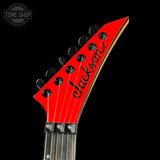 Close-up of a red Jackson guitar headstock on a black background