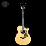 Acoustic guitar with a tortoiseshell pickguard on a black background, featuring the Tone Shop logo.