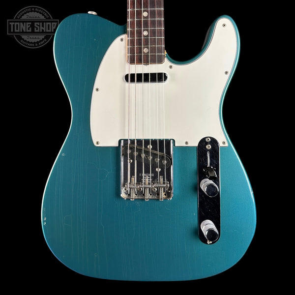 Blue electric guitar with a white pickguard on a black background, featuring the Tone Shop logo.
