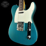 Blue electric guitar with a white pickguard on a black background, featuring the Tone Shop logo.