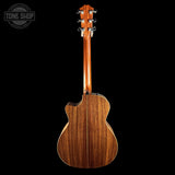 The back of a wooden acoustic guitar with a cutaway body and six tuning pegs, shown against a solid black background. A 'TONE SHOP' watermark is visible in the top-left corner.