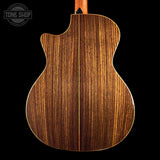 The back of a wooden acoustic guitar with a glossy, dark brown wood grain finish, shown against a solid black background with a Tone Shop watermark in the top left corner.
