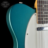 Close-up of a teal electric guitar with a black background