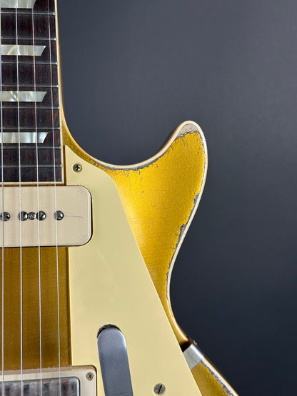 Close-up of a guitar with a gold pickguard on a dark background
