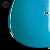 Close-up of a teal electric guitar with 'Tone Shop' logo in the corner.