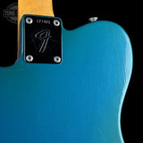 Close-up of a blue electric guitar with a Fender logo on the back.