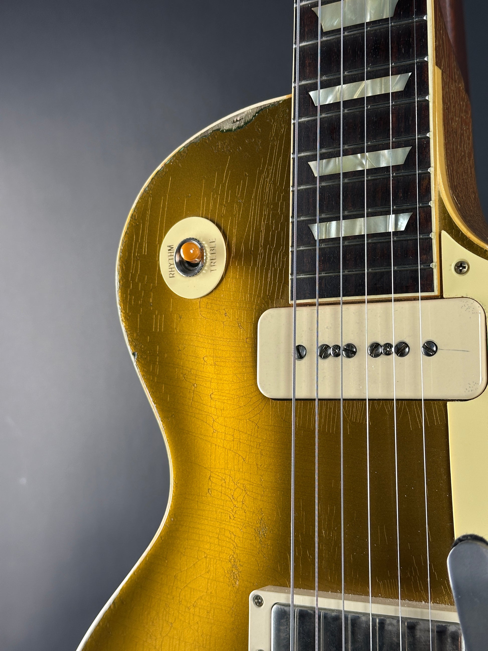 Close-up of a gold electric guitar on a gray background