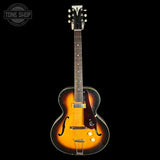 A classic electric guitar with a sunburst finish, featuring a black headstock and a dark fretboard, shown against a solid black background with a 'TONE SHOP' watermark in the top left corner.