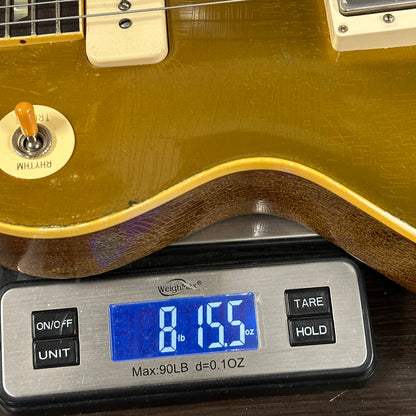 Guitar being weighed on a digital scale with a display showing weight.