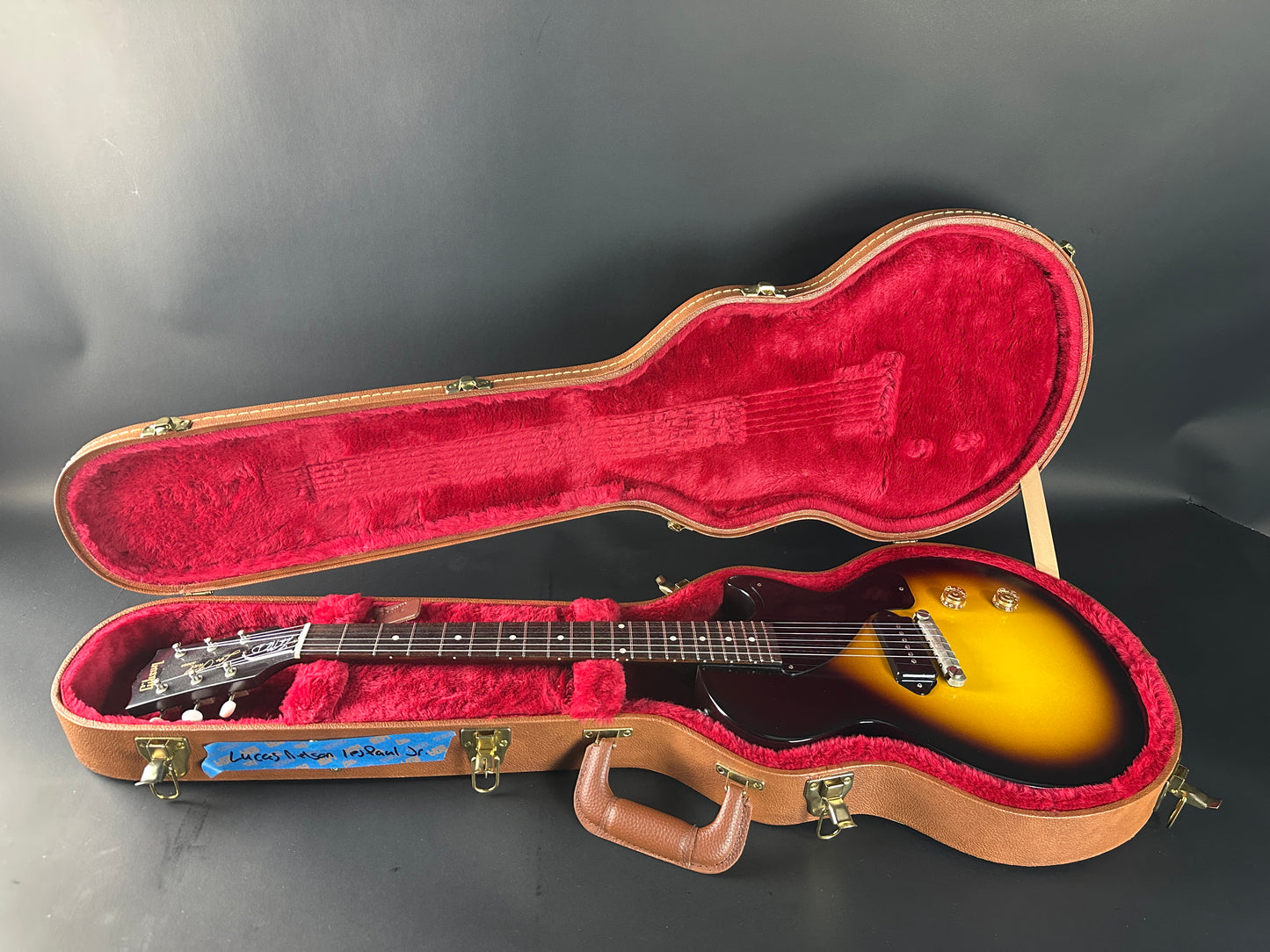 Guitar in an open case with a red interior on a gray background