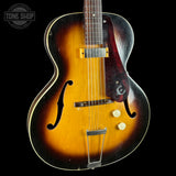 A classic hollow-body electric guitar with a sunburst finish, featuring a yellow-orange center and dark brown outer edges, set against a solid black background.